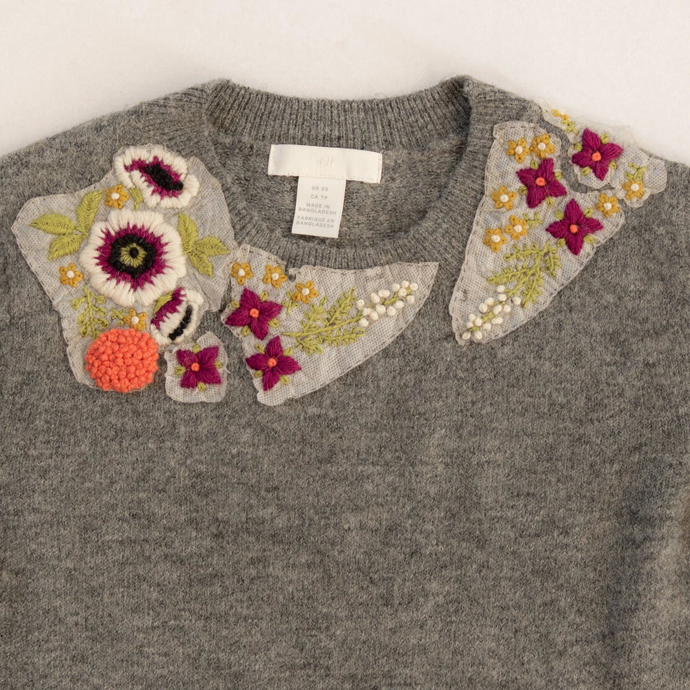 Gray sweater with floral embellishments on a white background