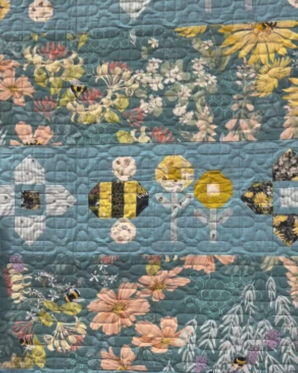 Floral quilt with a blue background featuring various flowers and bees.