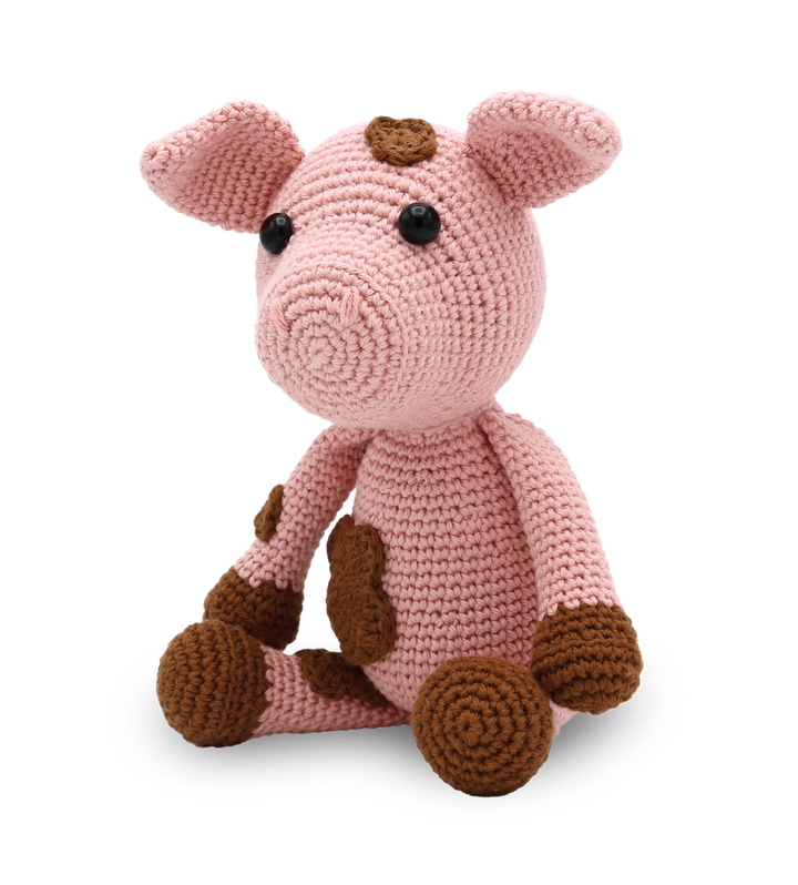 Crocheted pink pig toy with brown accents on a white background