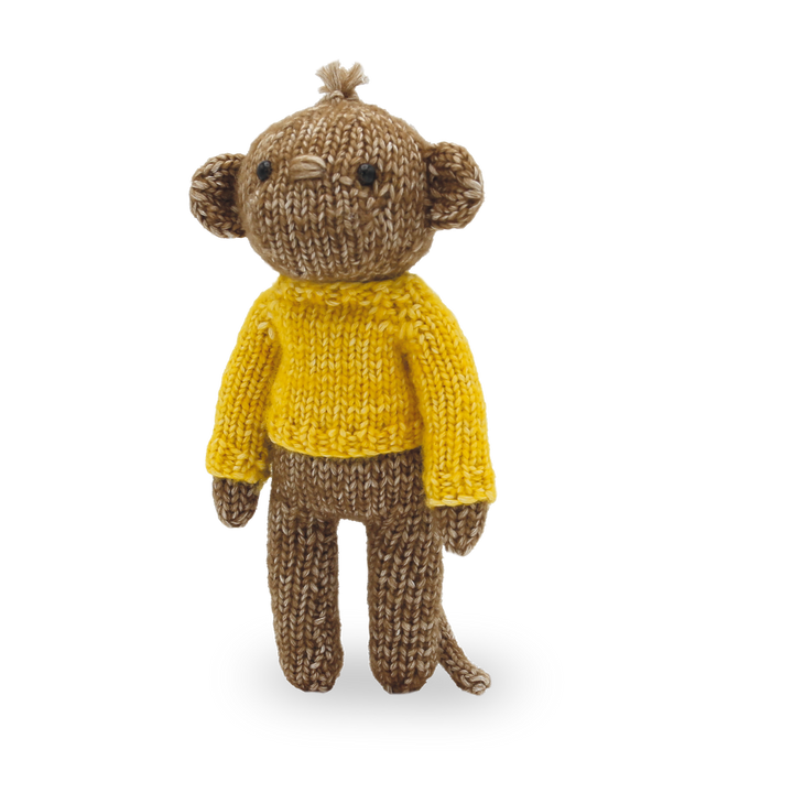 Knitted monkey toy wearing a yellow sweater on a white background