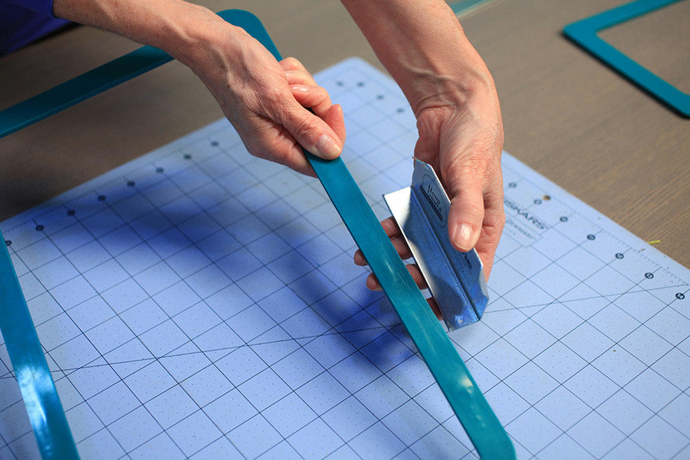 Person using a blue cutting tool on a grid surface