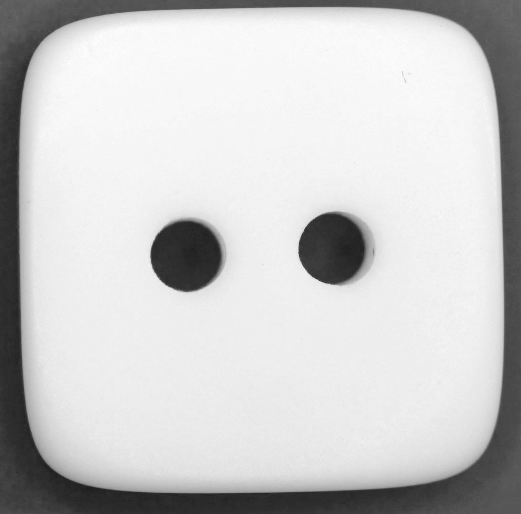 White square button with two holes on a dark background