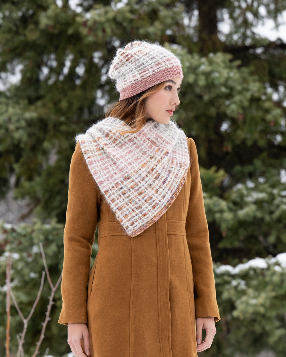 Woman wearing a knitted hat and scarf in a snowy forest setting