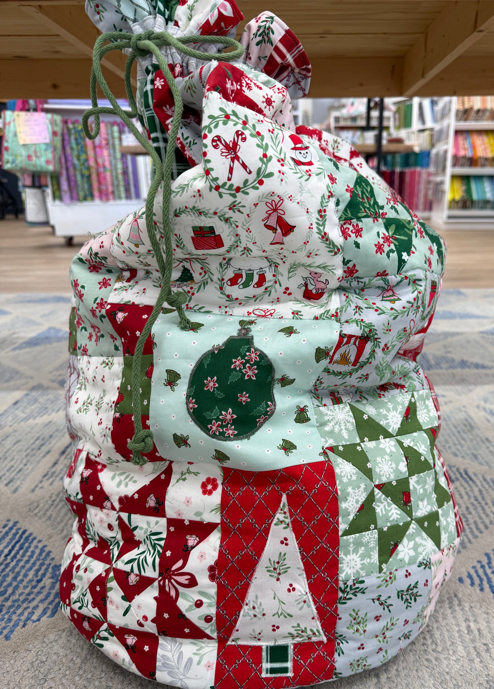 Quilted drawstring bag with Christmas pattern on a carpeted floor.