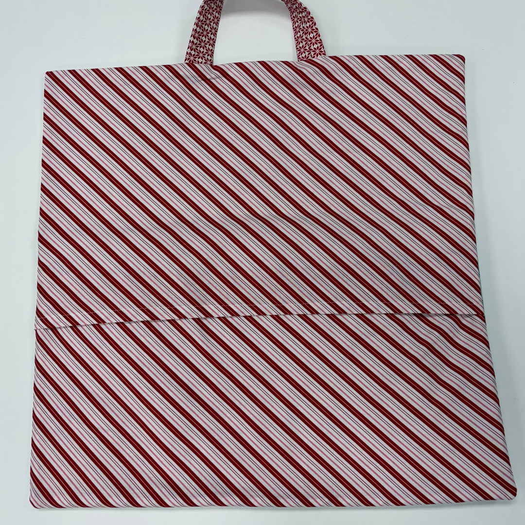 Red and white striped bag with a handle on a light gray background