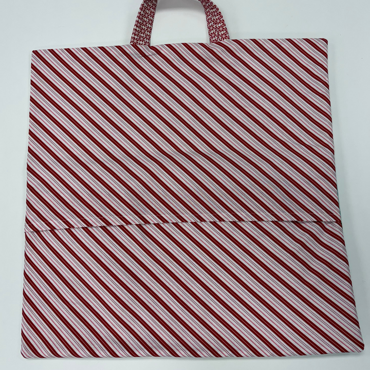 Red and white striped bag with a handle on a light gray background