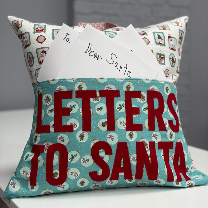 Decorative pillow with 'Letters to Santa' text and a card on top, against a neutral background.