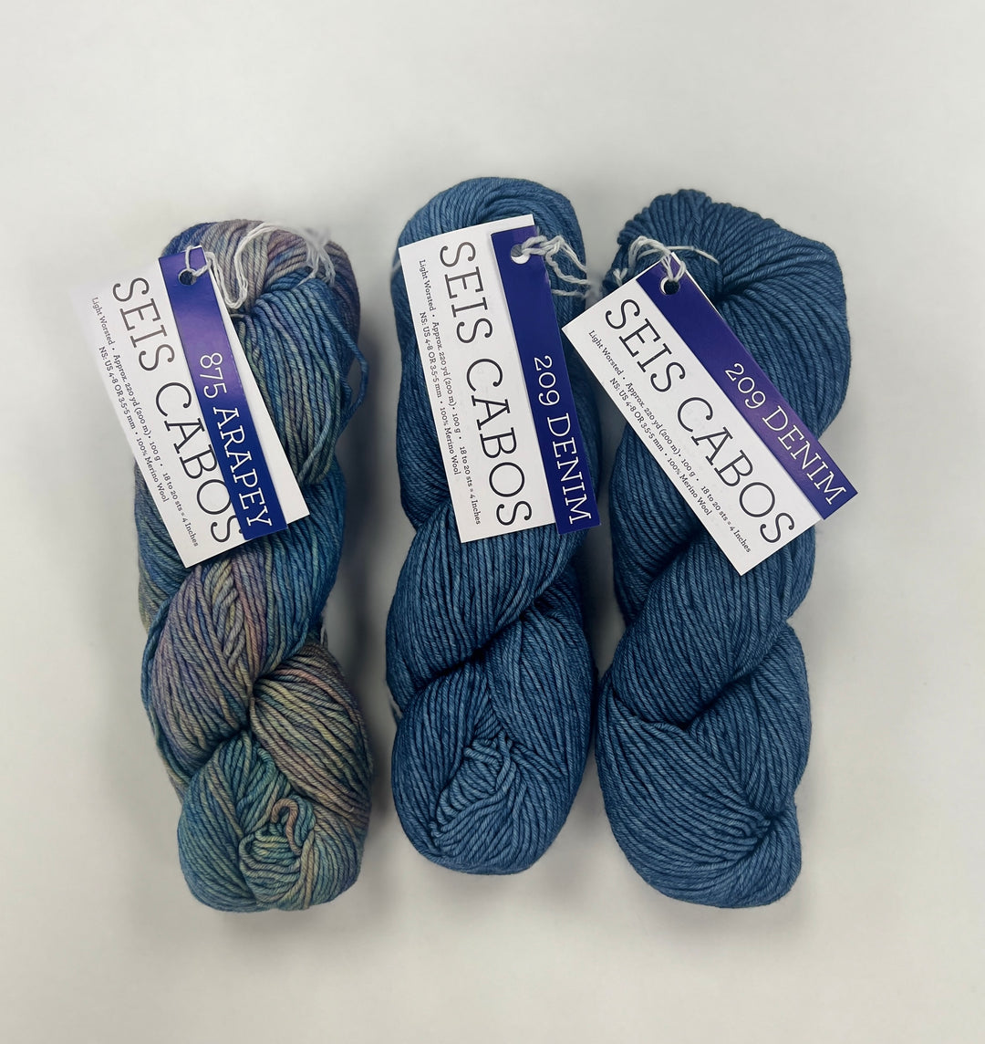 Three skeins of blue yarn with labels on a white background