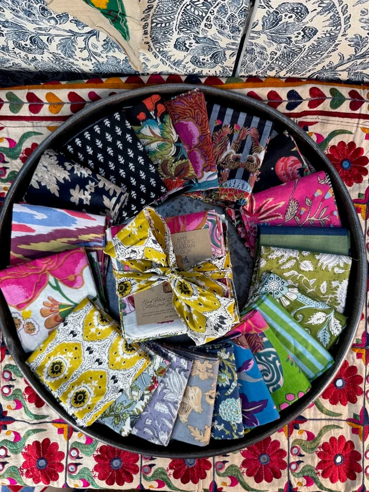 Collection of colorful fabric samples arranged in a circular pattern on a floral-patterned surface.