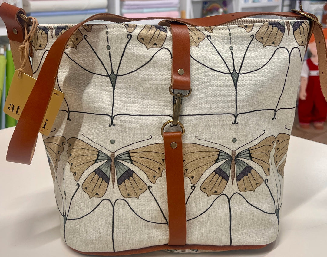 Bag with butterfly design and brown straps on a white surface