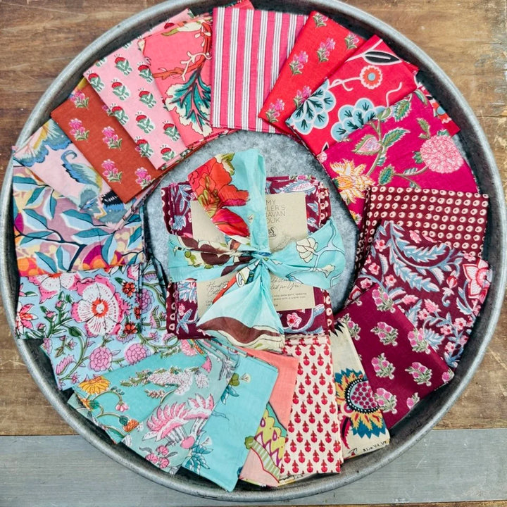 Collection of colorful fabric squares in a metal tray on a wooden surface