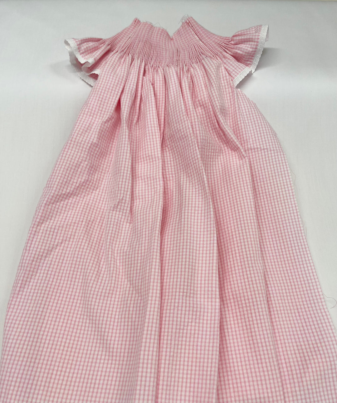 pleated pink gingham bishop dress on a white background