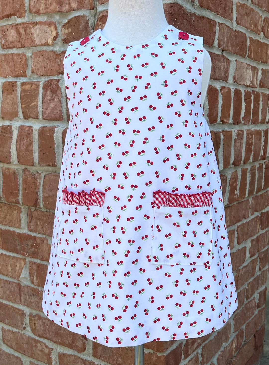 White dress covered in cherries with pockets and red ruffle trim