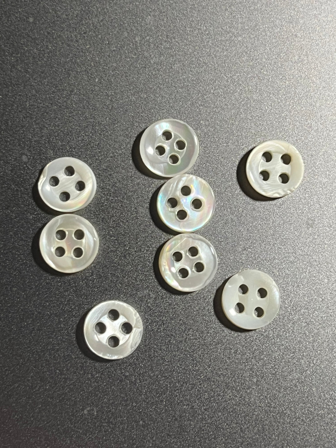 Pearl  buttons with four holes on a dark surface