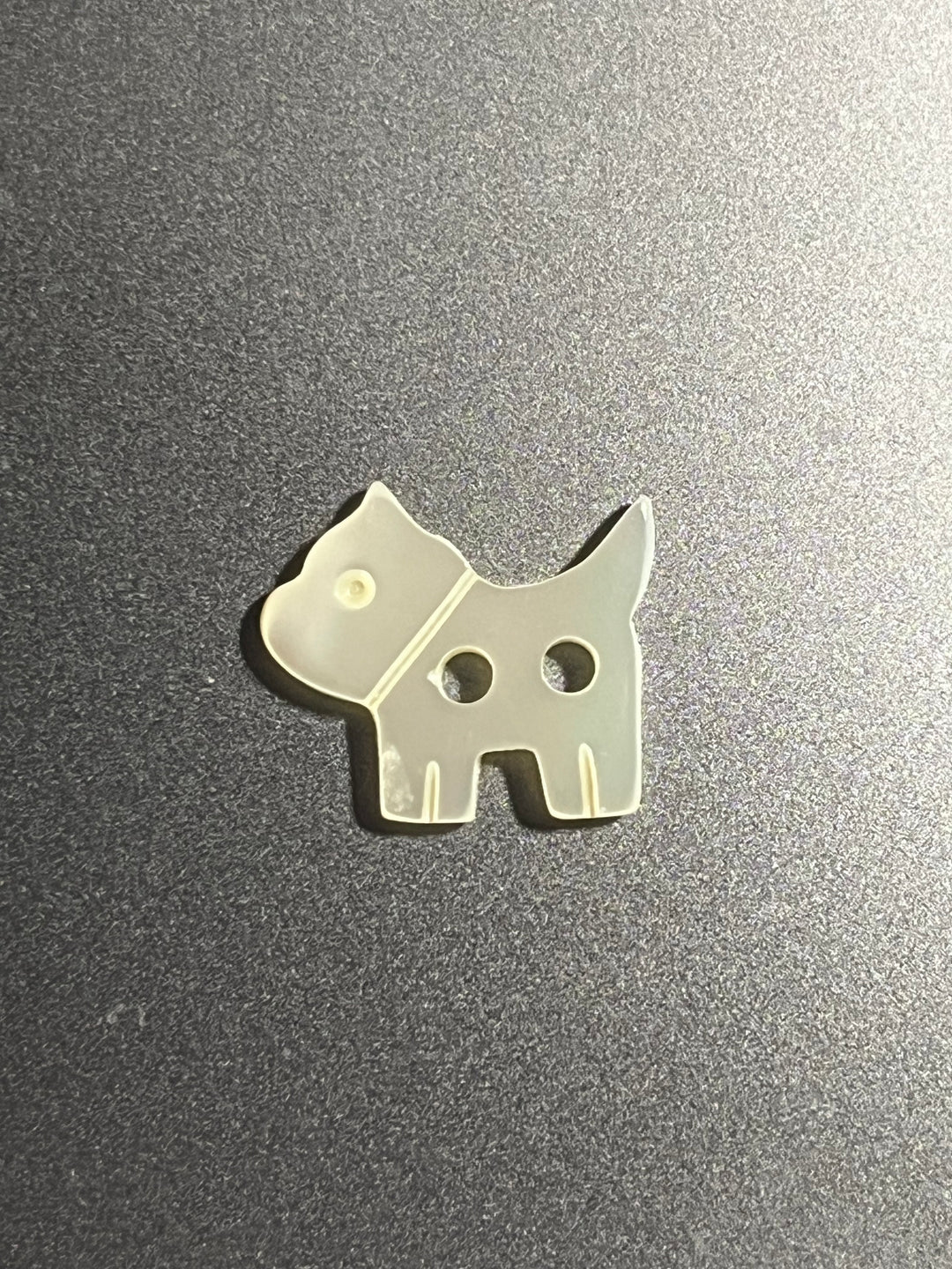 Dog carved button on grey surface