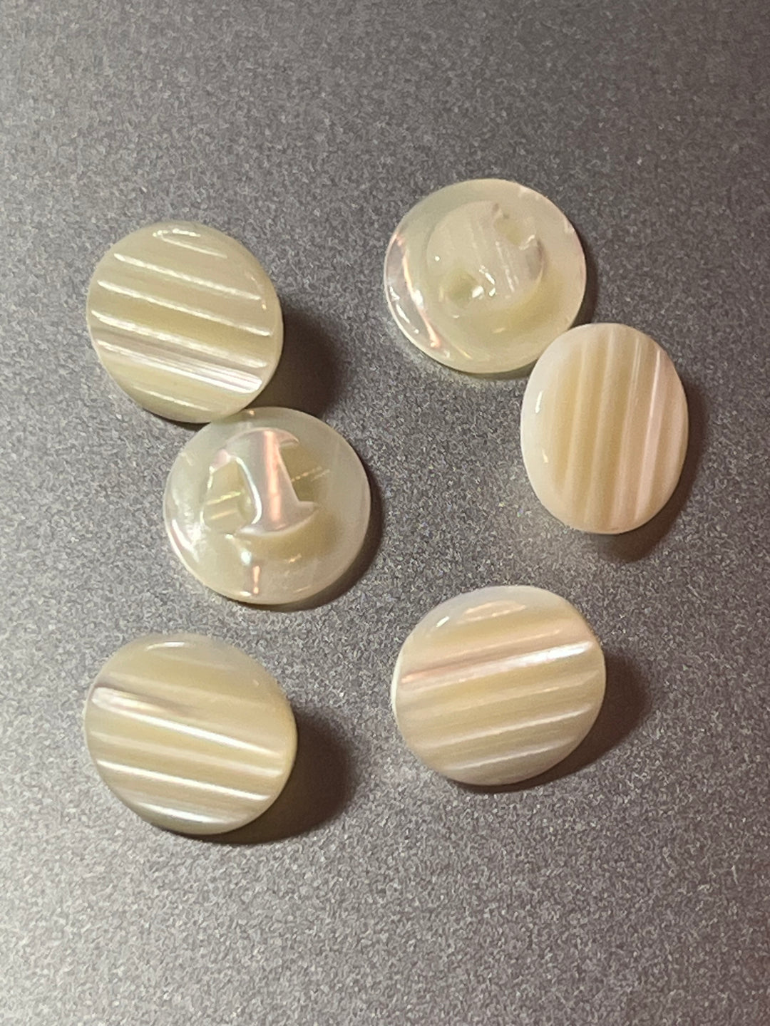 Set of six pearl buttons with striped pattern on a gray background
