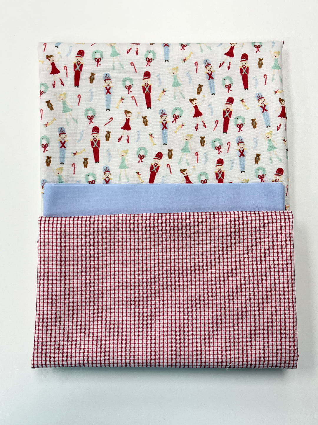 Folded fabric with Christmas-themed pattern and red checkered border on a white background