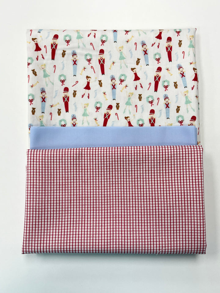 Folded fabric with Christmas-themed pattern and red checkered border on a white background