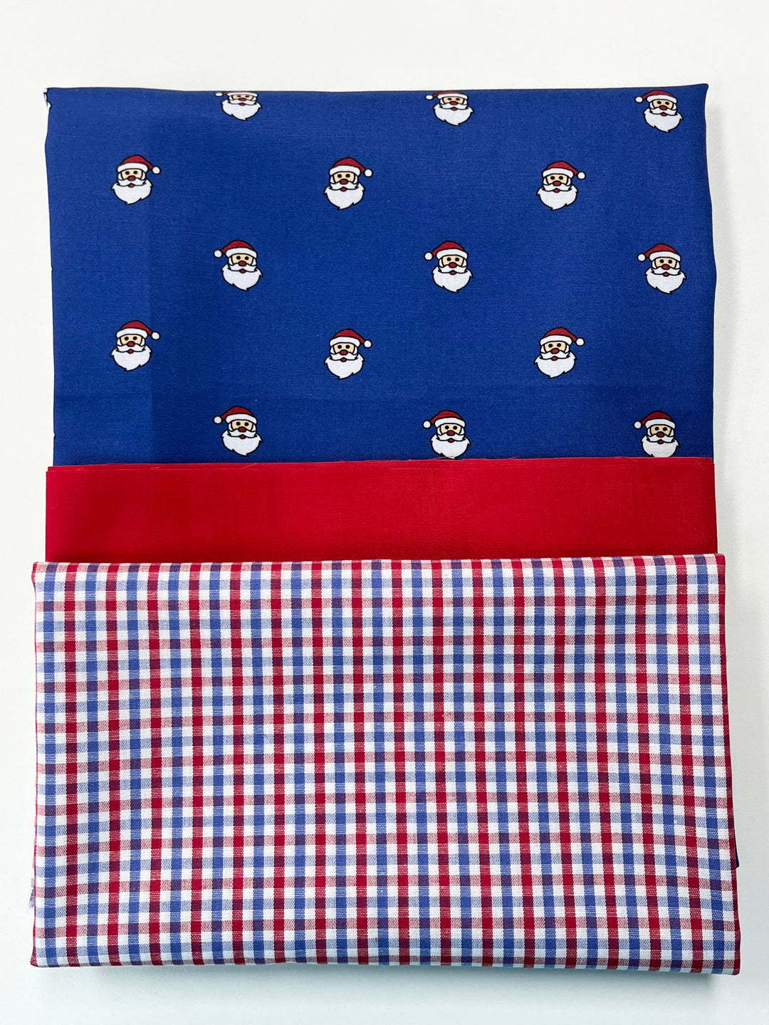 Folded fabric with Santa Claus pattern on blue, red, and checkered patterns.