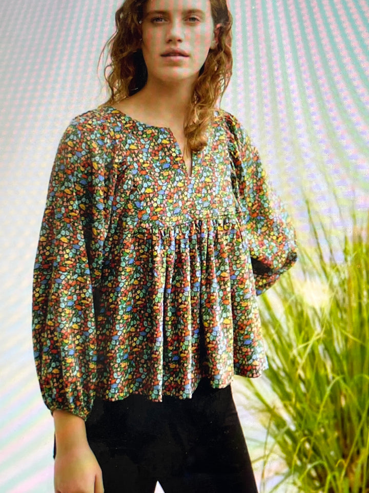 Woman wearing a colorful gathered top with a blurred background