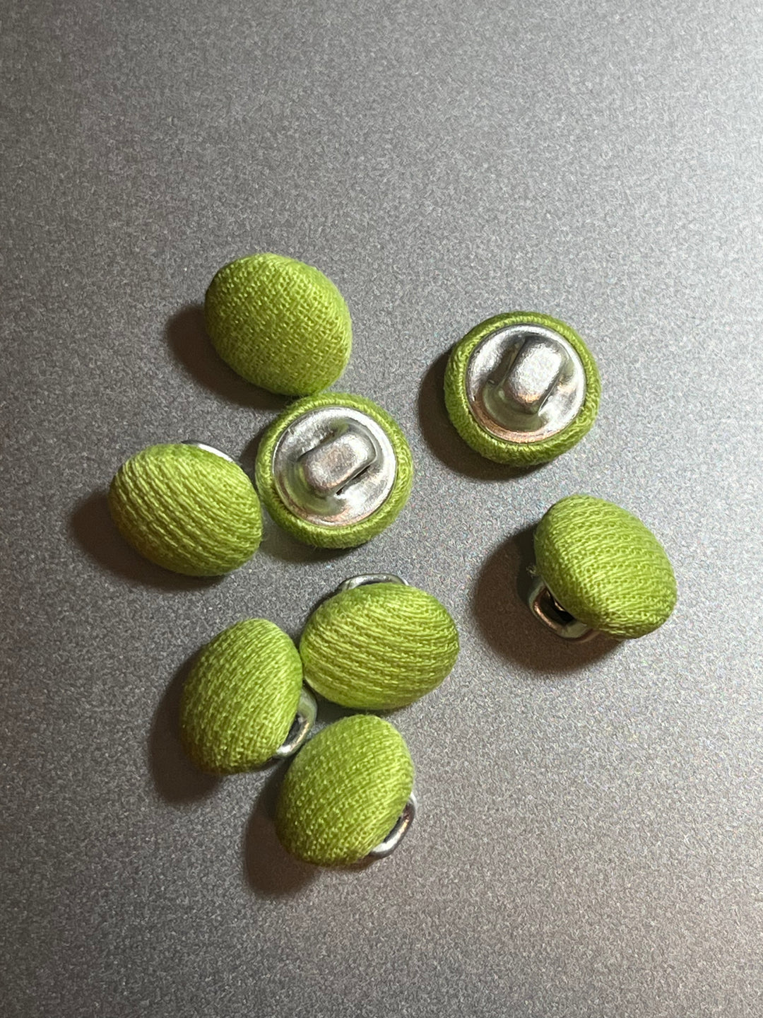 Green buttons with metal backs on a gray surface