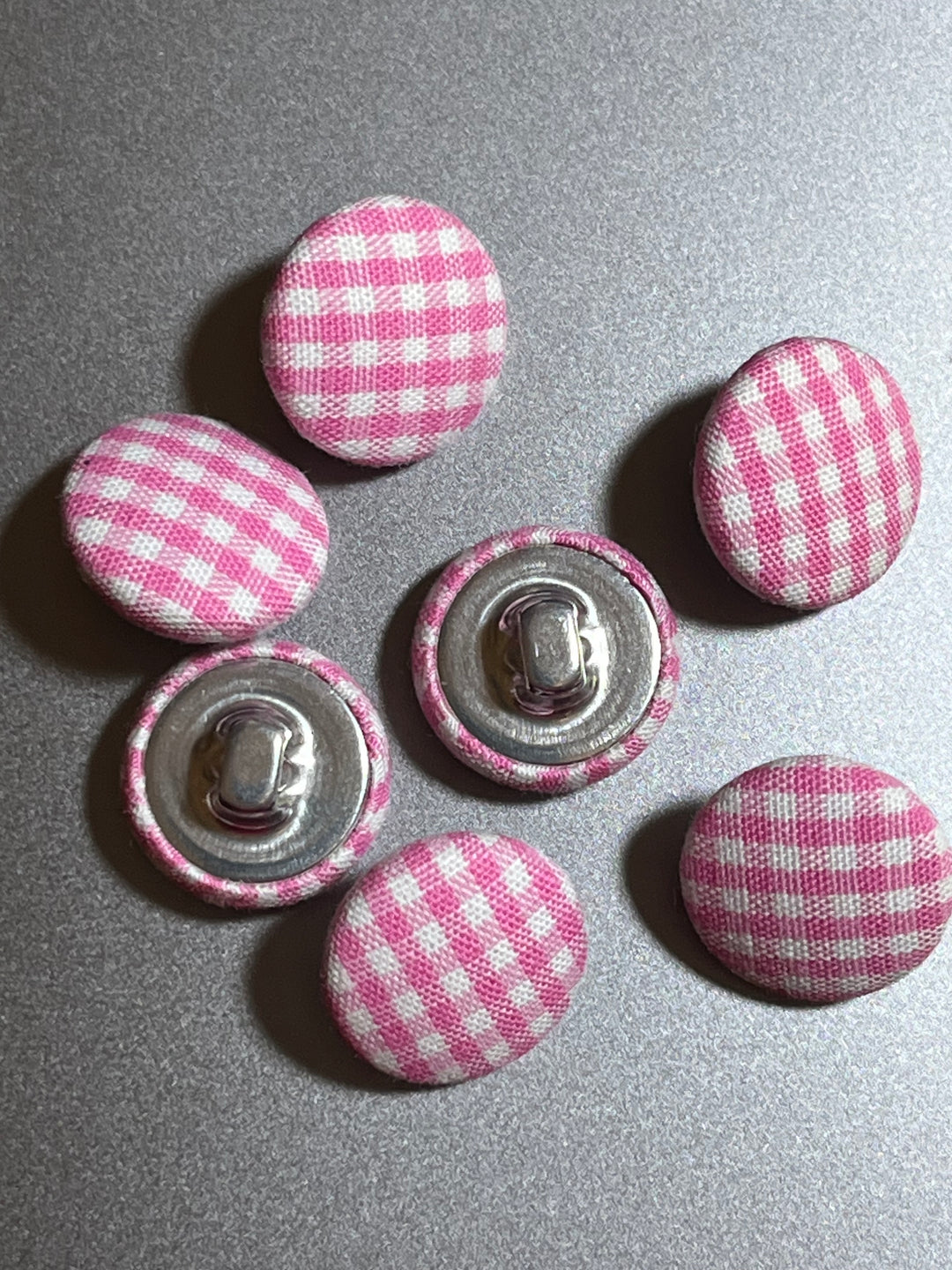 Pink and white checkered buttons on a gray surface