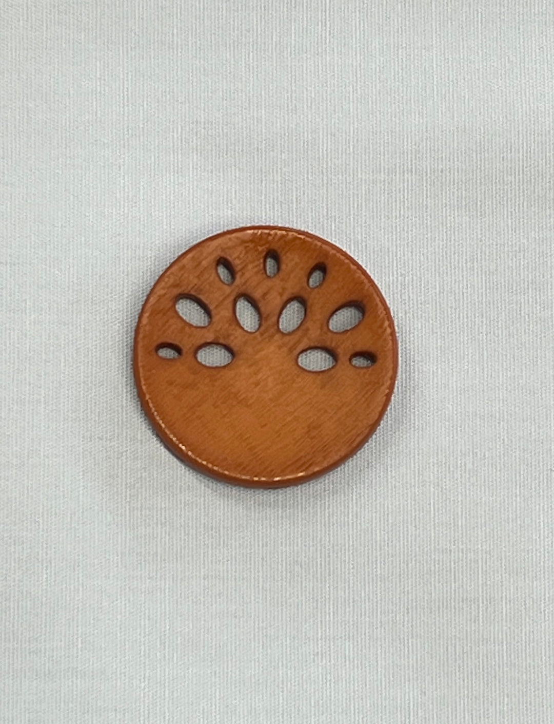 Brown round button with a paw print design on a light gray background