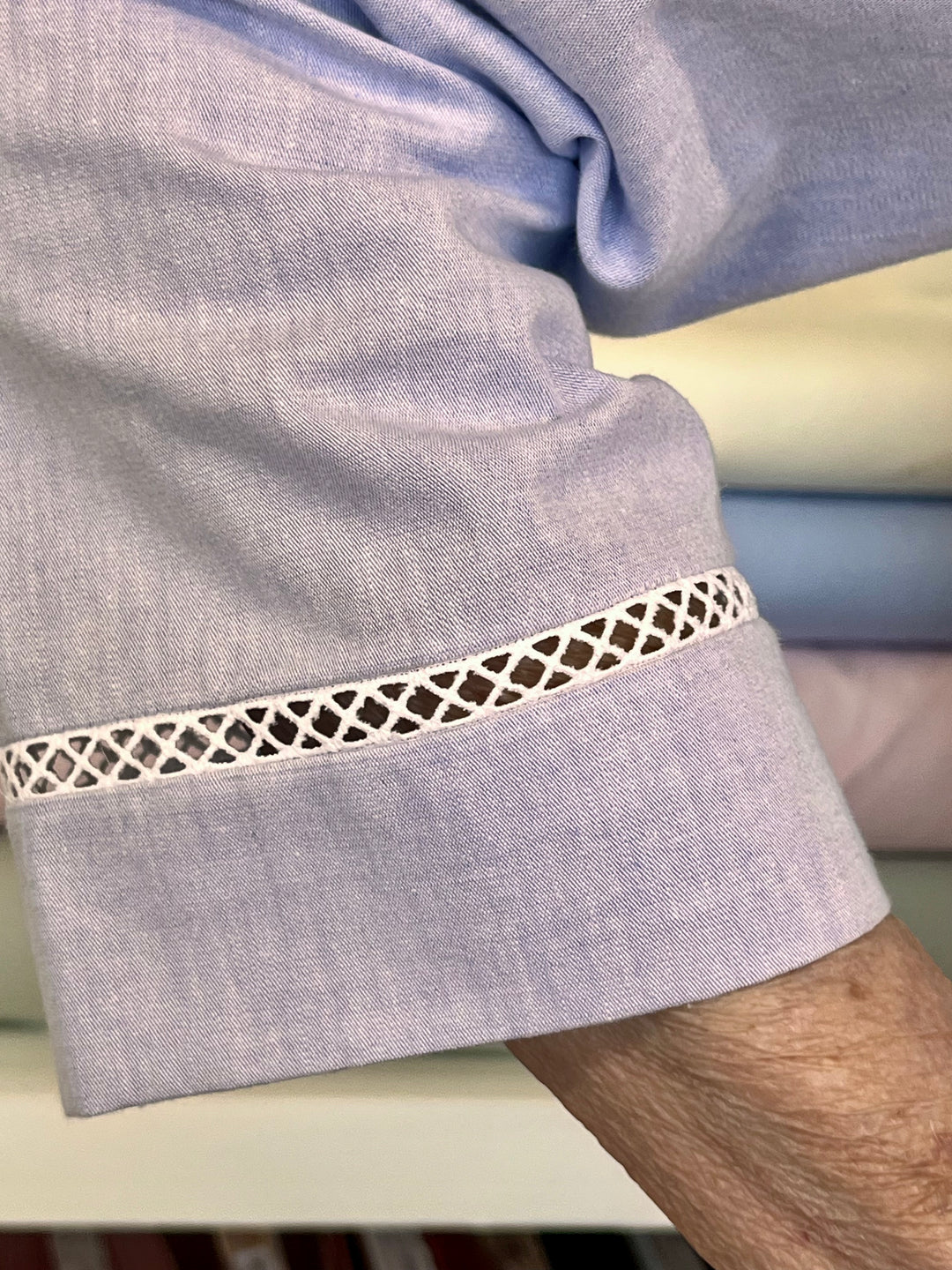 Close-up of a light purple garment with decorative white trim on a neutral background