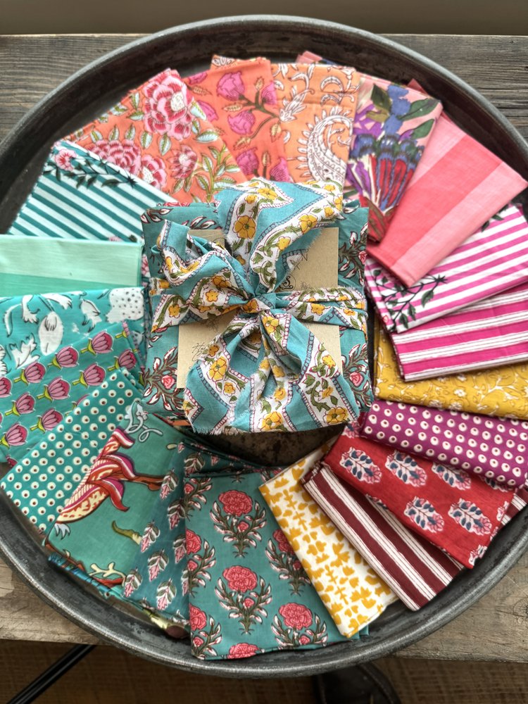 Assorted colorful fabric samples arranged in a circular pattern on a dark surface.