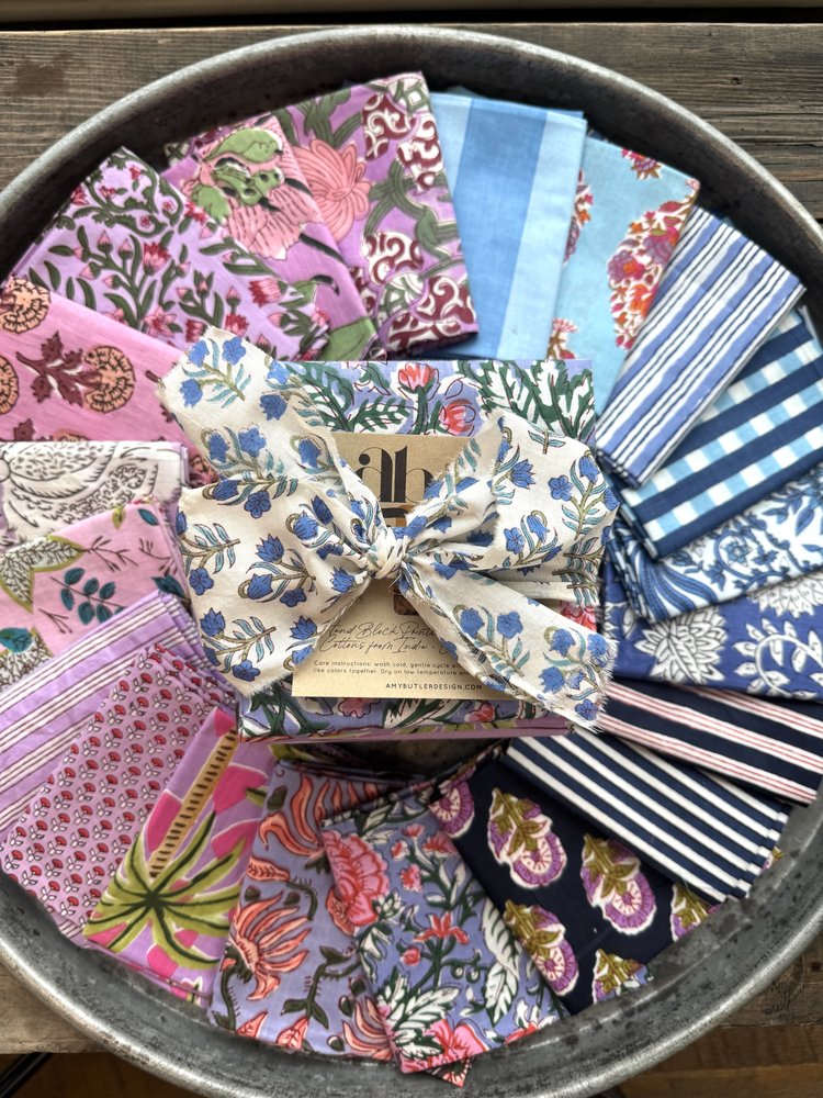 Collection of colorful fabric samples in a metal tray on a wooden surface
