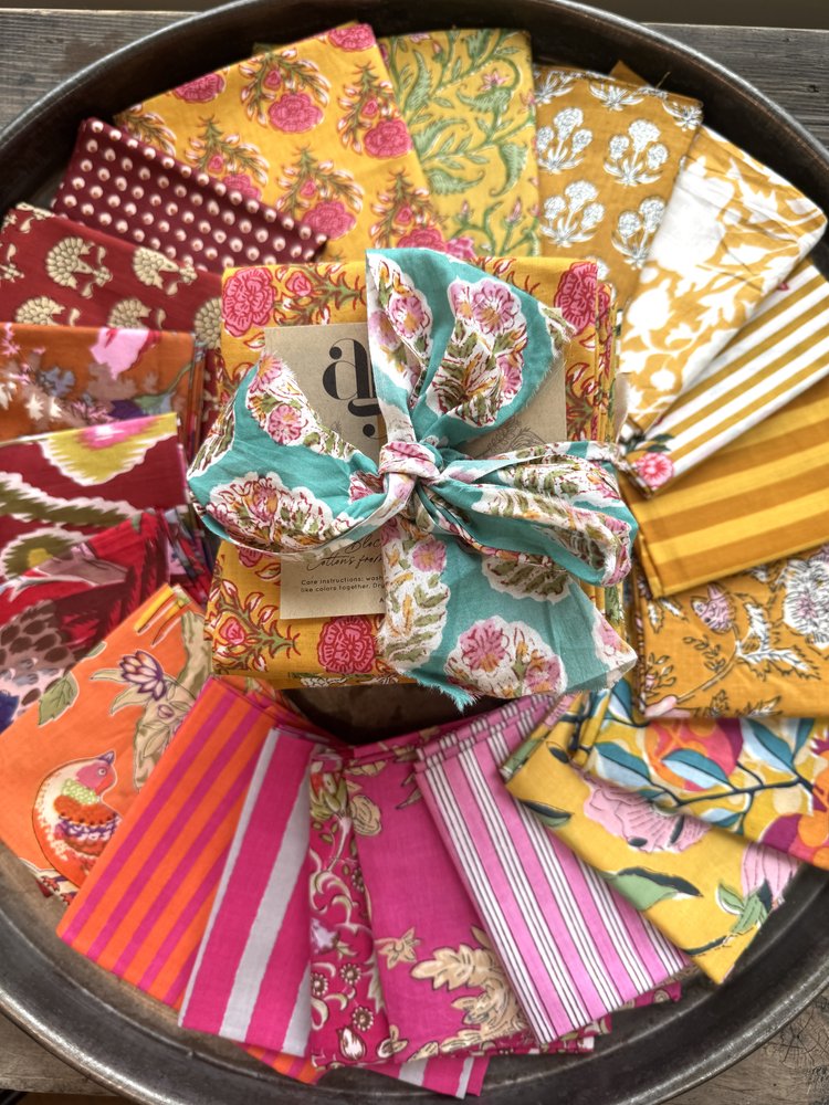 Assorted colorful fabric squares in a metal tray