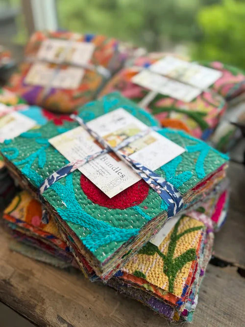 Stack of colorful fabric books with tags on a wooden surface
