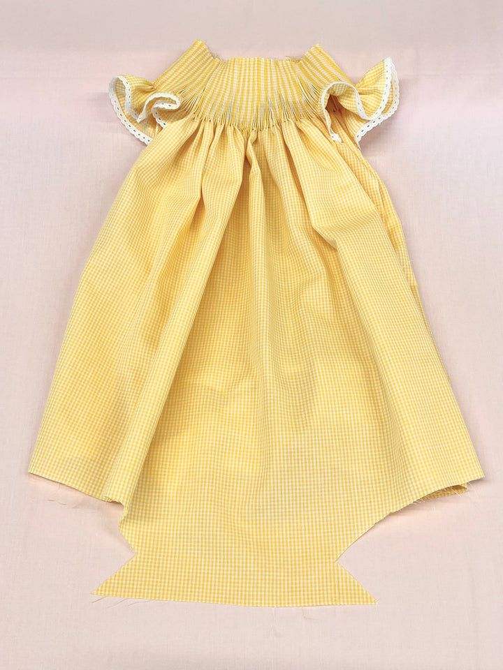 Yellow checkered dress with ruffled sleeves on a beige background