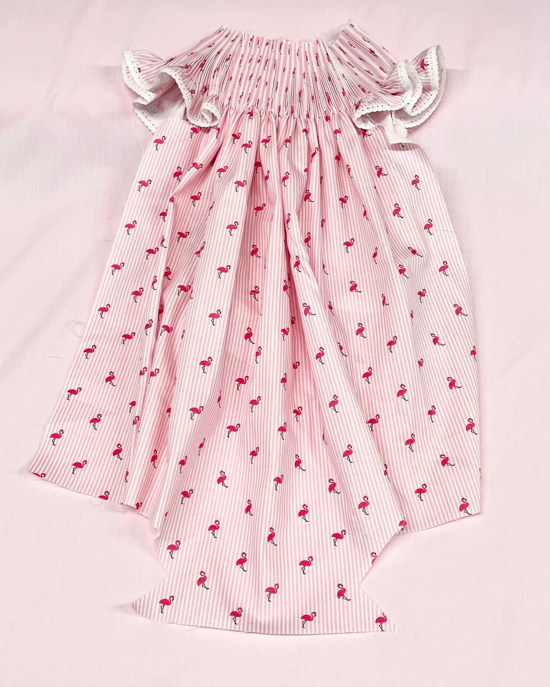 Pink dress with flamingo pattern on a light pink background