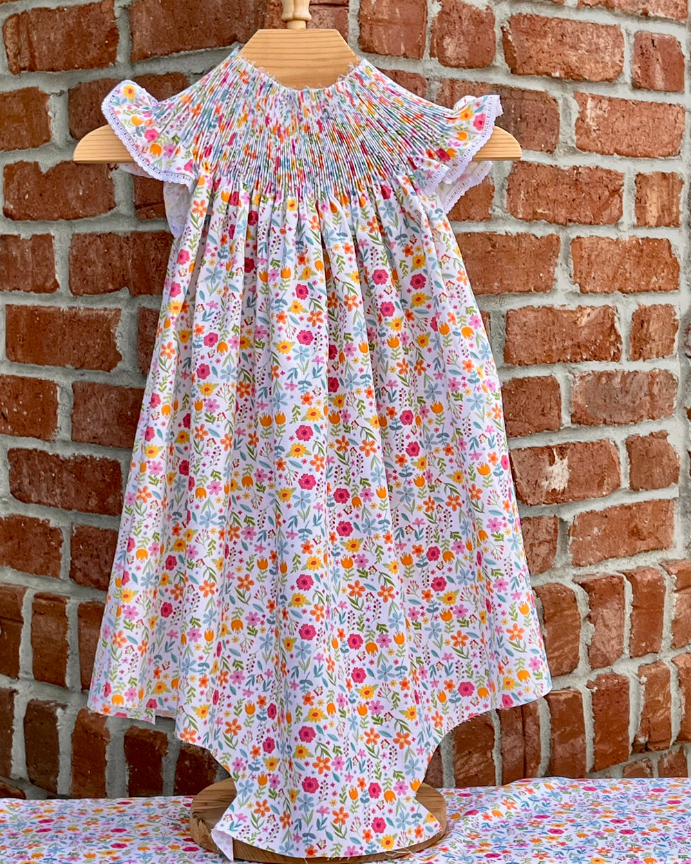 Floral dress on a mannequin against a brick wall