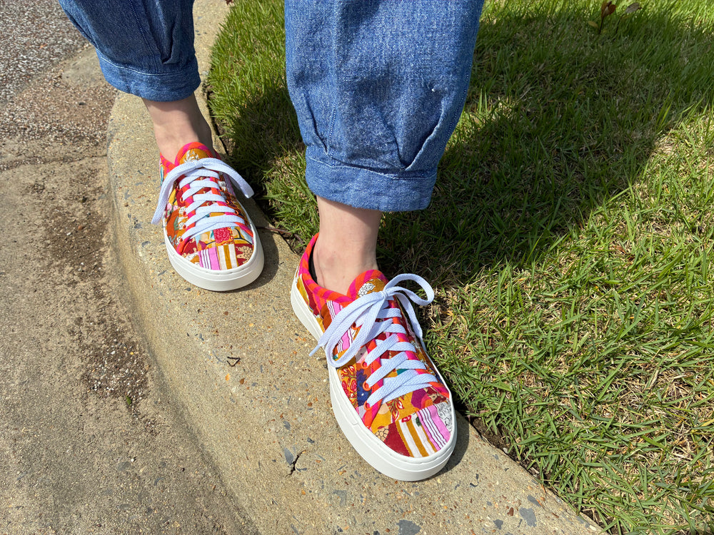 Colorful sneakers with white laces worn on a concrete surface with grass in the background