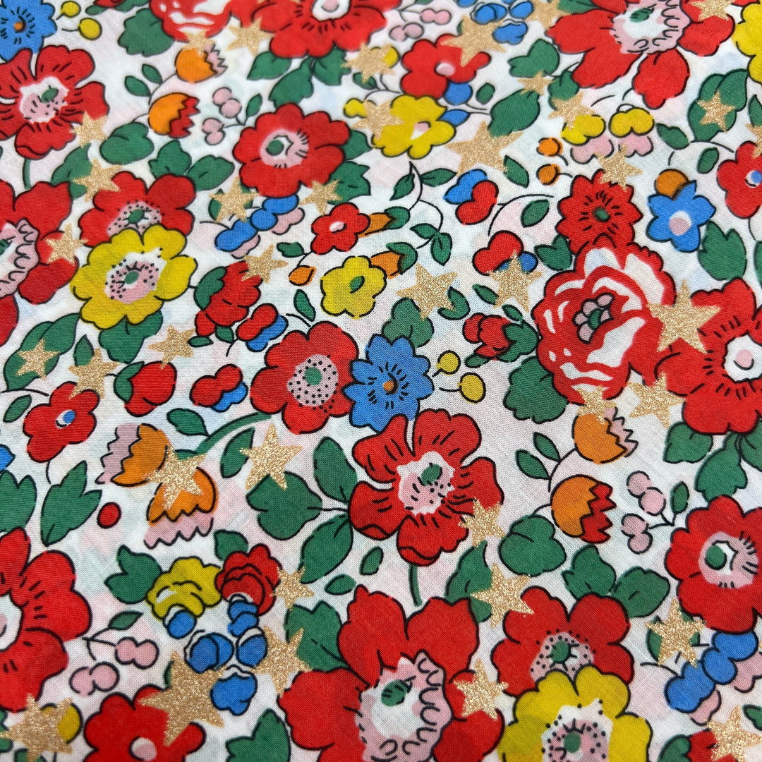 Liberty of London floral fabric with red, yellow, and blue flowers. Gold metallic stars scattered throughout.