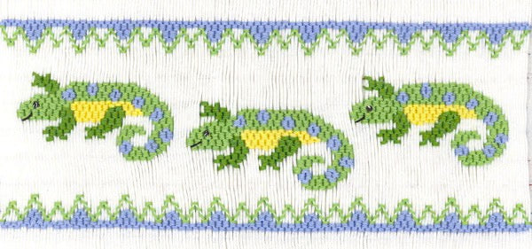 Smocking plate with three geckos and geometric design at top and bottom. 8 1/2 rows of smocking on a yoke.