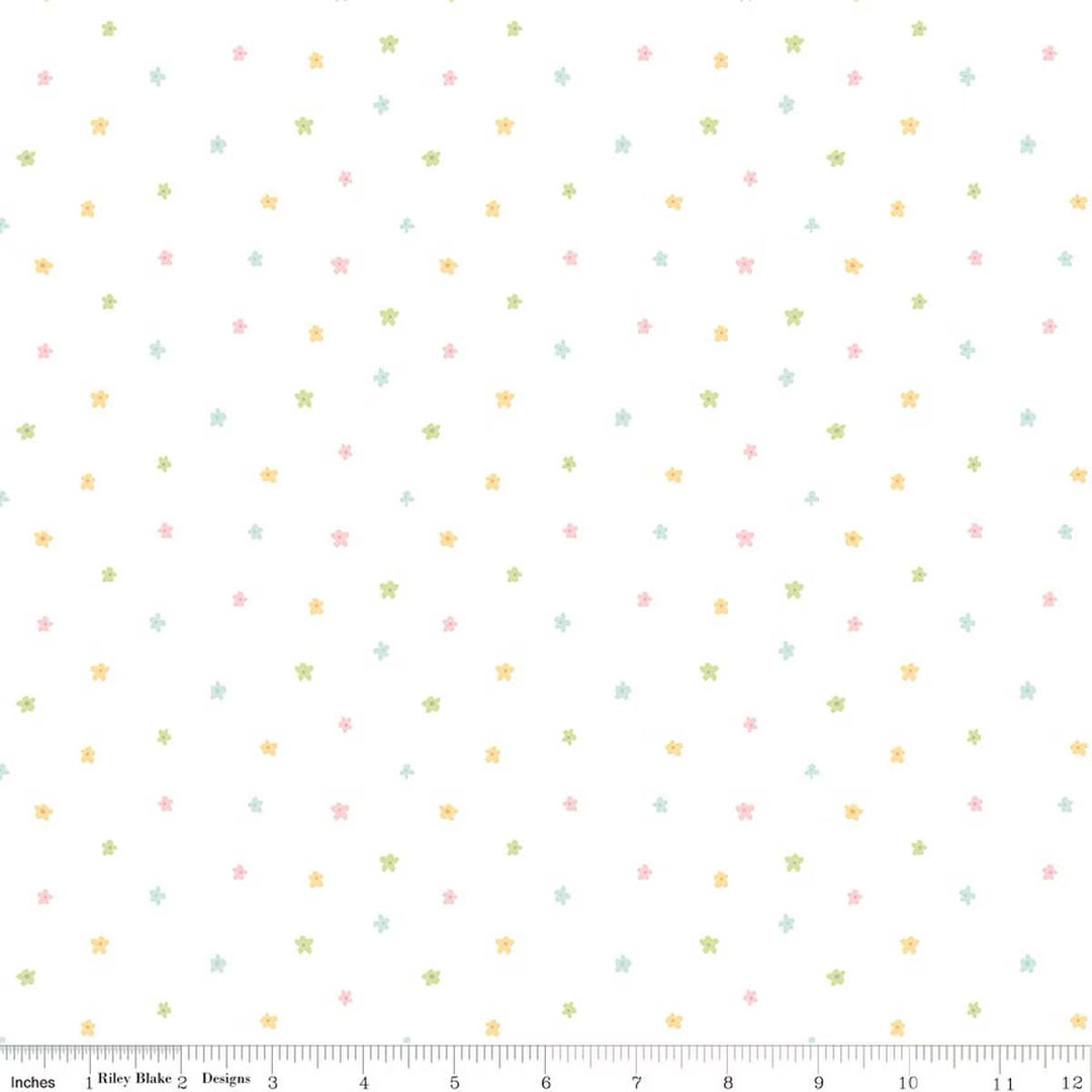 Fabric swatch of scattered blossoms on a white background with a ruler on the bottom for scale. 