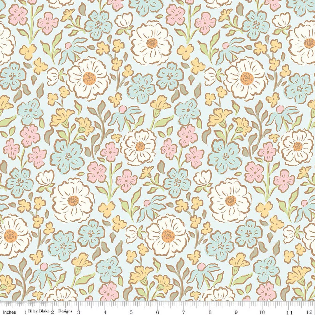 A repeating floral pattern on a pale blue background with white, pink, and light blue flowers, yellow accents, and brown outlines. A ruler along the bottom edge shows the scale of the pattern.