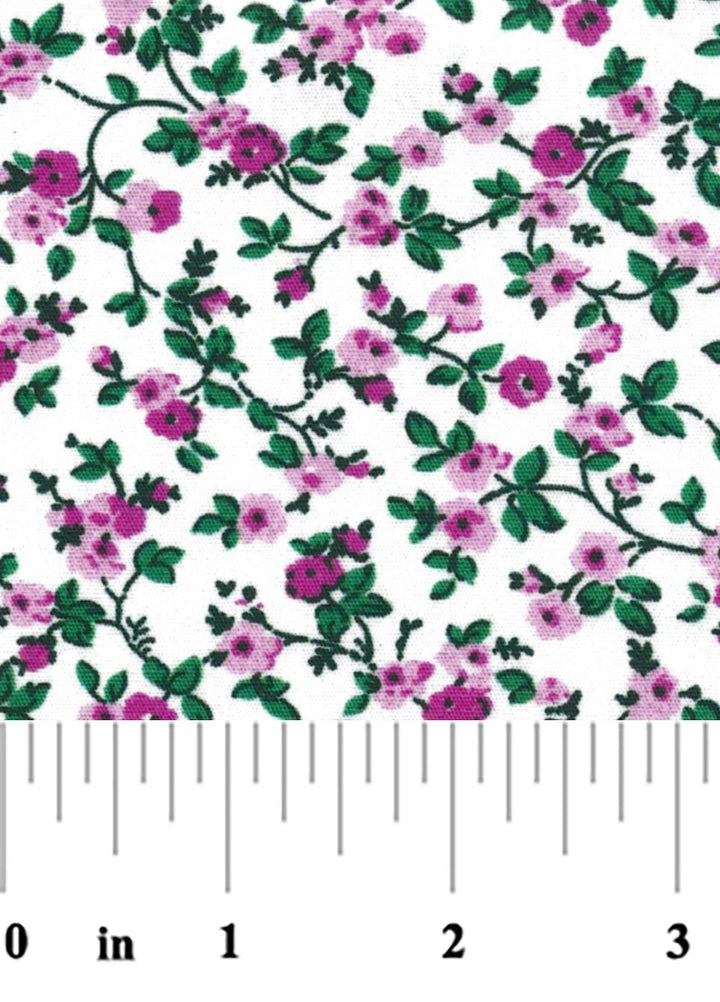 A close-up of a white fabric or material printed with a repeating floral vine pattern in pink and green, with a ruler along the bottom edge showing inch measurements.