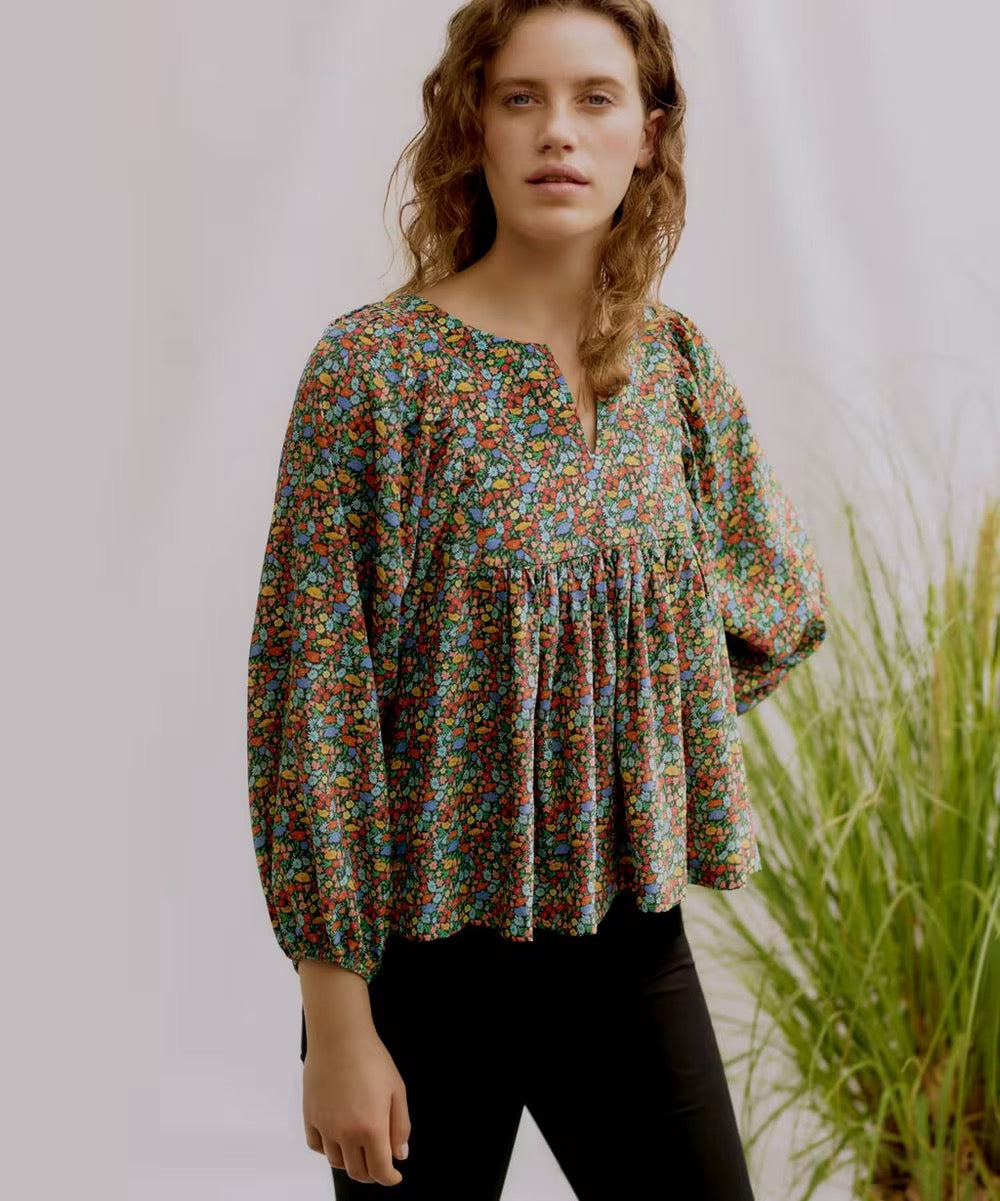 Woman wearing a floral blouse with a blurred natural background