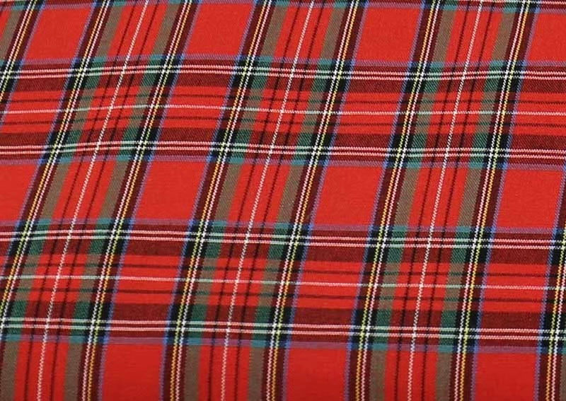 A close-up of a red tartan plaid fabric pattern with intersecting black, green, yellow, and white stripes.