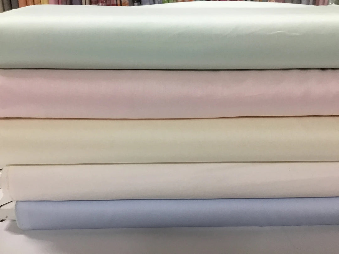 Stack of pastel-colored fabrics on a neutral background