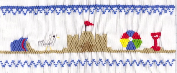 Smocking plate with a beach scene including a sand castle, beach ball, seagull, pail and shovel. 7 1/2 rows of smocking on a yoke.