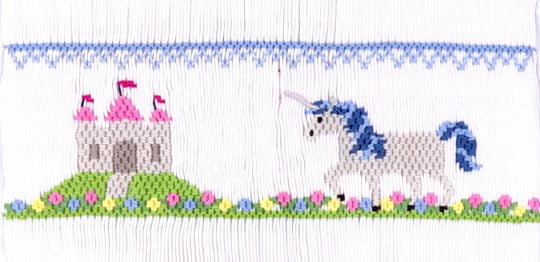 Smocking plate with a unicorn approaching a castle on a hill. 7.5 rows of smocking on a yoke.
