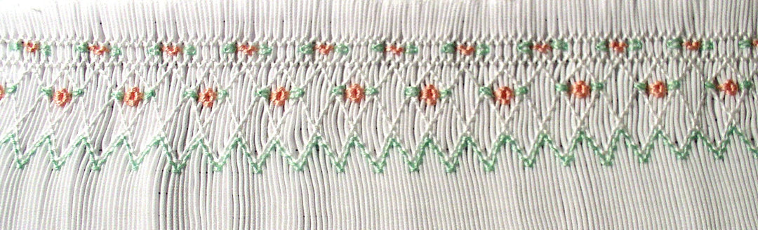 Smocking plate with a geometric design and small flowers on a bishop designed for preemies and newborns.