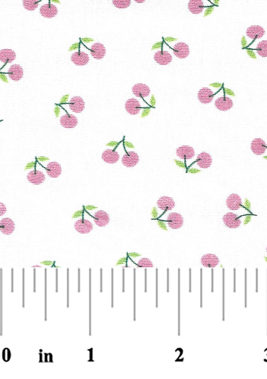 pink cherries with green leaves and stems on a white background with a ruler at the bottom for scale