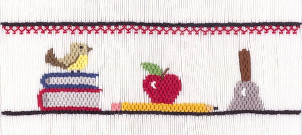 Smocking plate with school supplies - books, an apple, a pencil and a bell. 7 rows of smocking on a yoke.