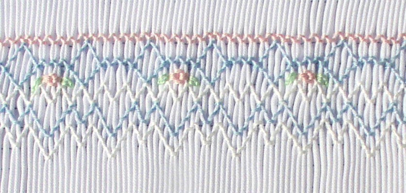Smocking plate with a geometric design and small flowers on a bishop designed for preemies and newborns.